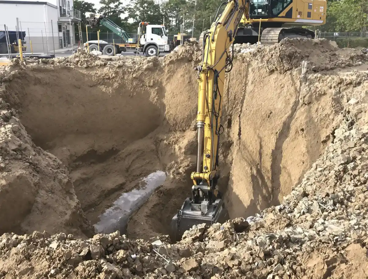 Large excavator digging a deep commercial foundation excavation with exposed clay walls in Kansas City