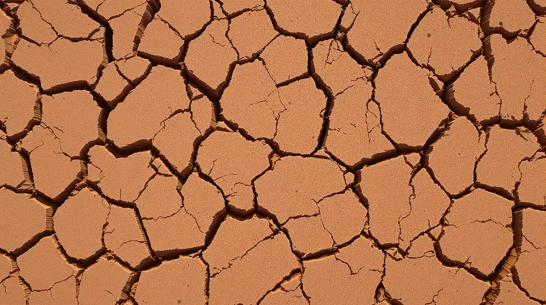 Close-up of red-brown Kansas City expansive clay soil with visible shrinkage cracks on a commercial construction site